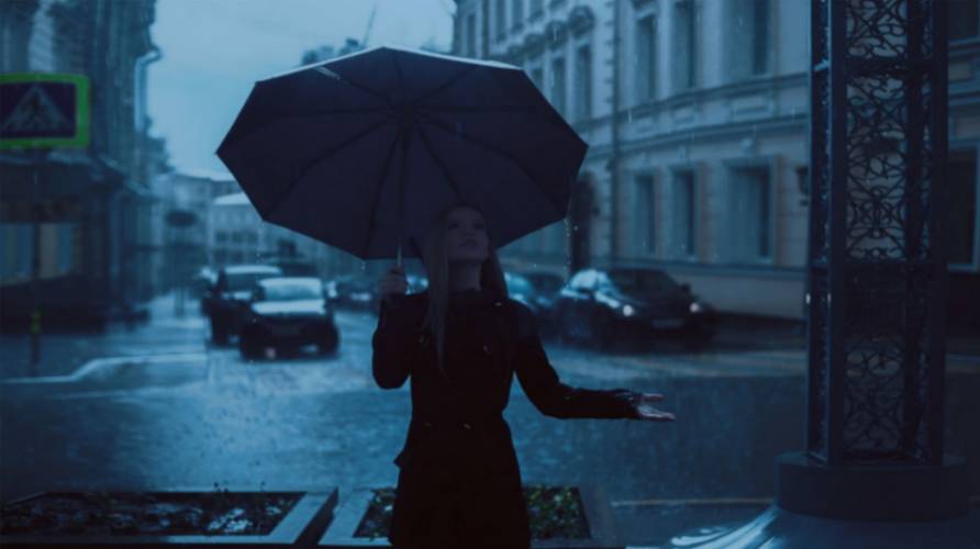 A woman with an umbrella standing in the rain represents a writer needing to not over-describe a scene.